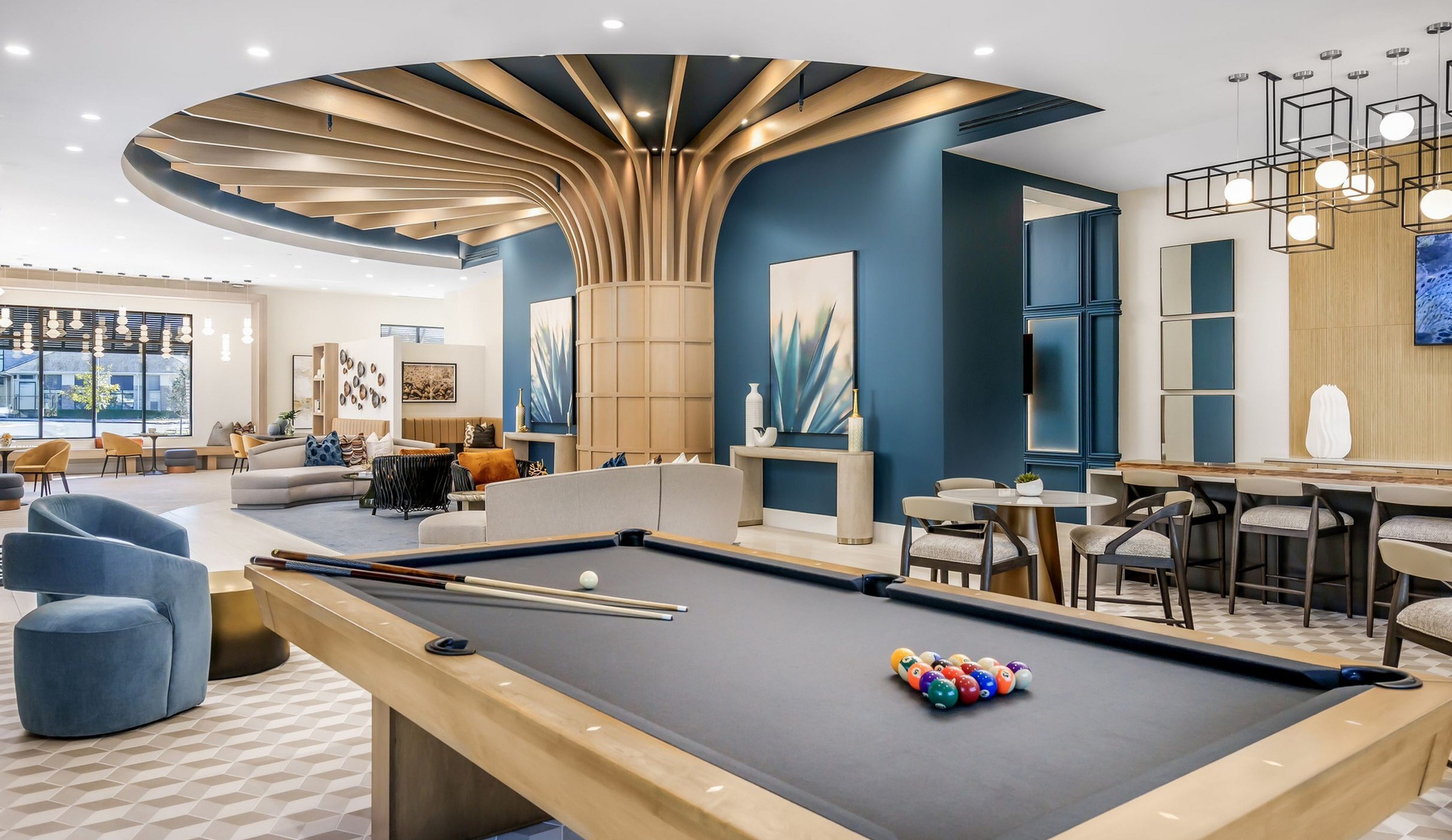 Elegant modern lounge area featuring chic furniture, a stylish pool table, and artistic decor with geometric lighting.