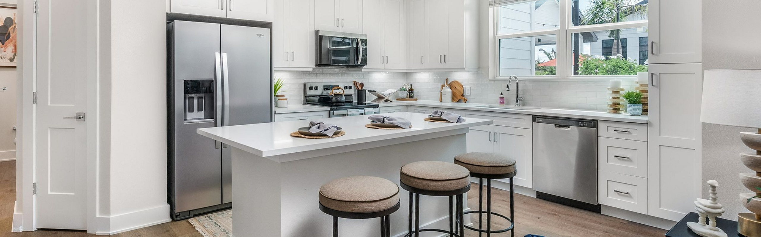 Modern kitchen design featuring sleek white cabinets, stainless steel appliances, and a stylish island with seating. Bright, inviting space with elegant lighting and contemporary decor.