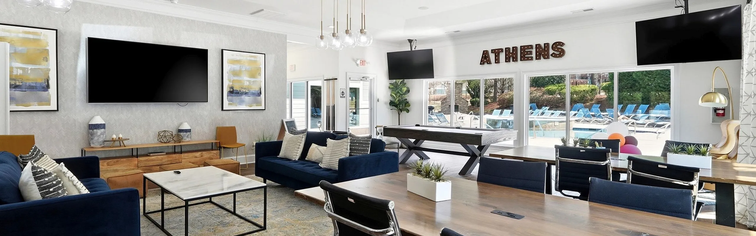 Bright and spacious apartment lounge with modern decor, featuring comfortable seating, stylish artwork, and a view of an inviting outdoor pool area.