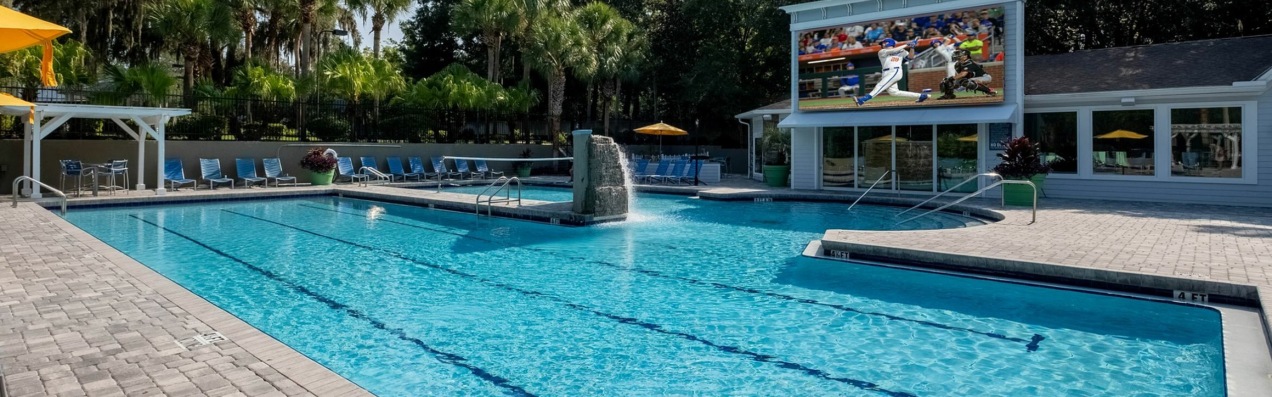 Luxurious outdoor pool area with spacious deck, surrounded by lush greenery, perfect for relaxation and entertainment.