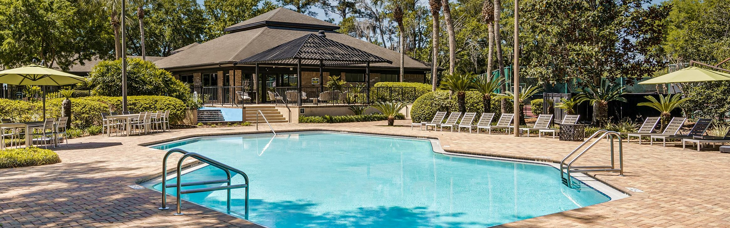 Inviting outdoor pool area with elegant lounge chairs and lush greenery, perfect for relaxation and leisure.
