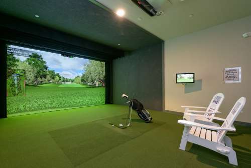 Indoor golf simulator room featuring lush virtual greens, cozy seating, and elegant decor for a luxurious living experience.
