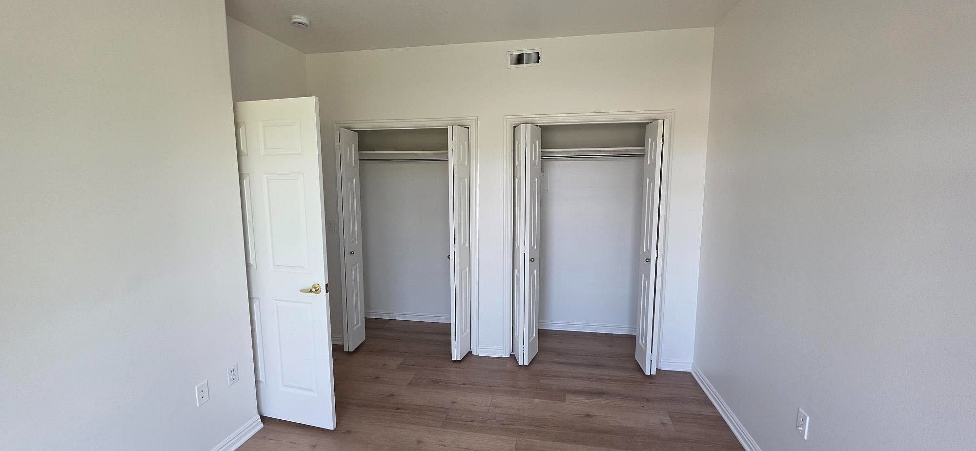 Bright apartment room with dual closets and elegant wood flooring, perfect for modern living.