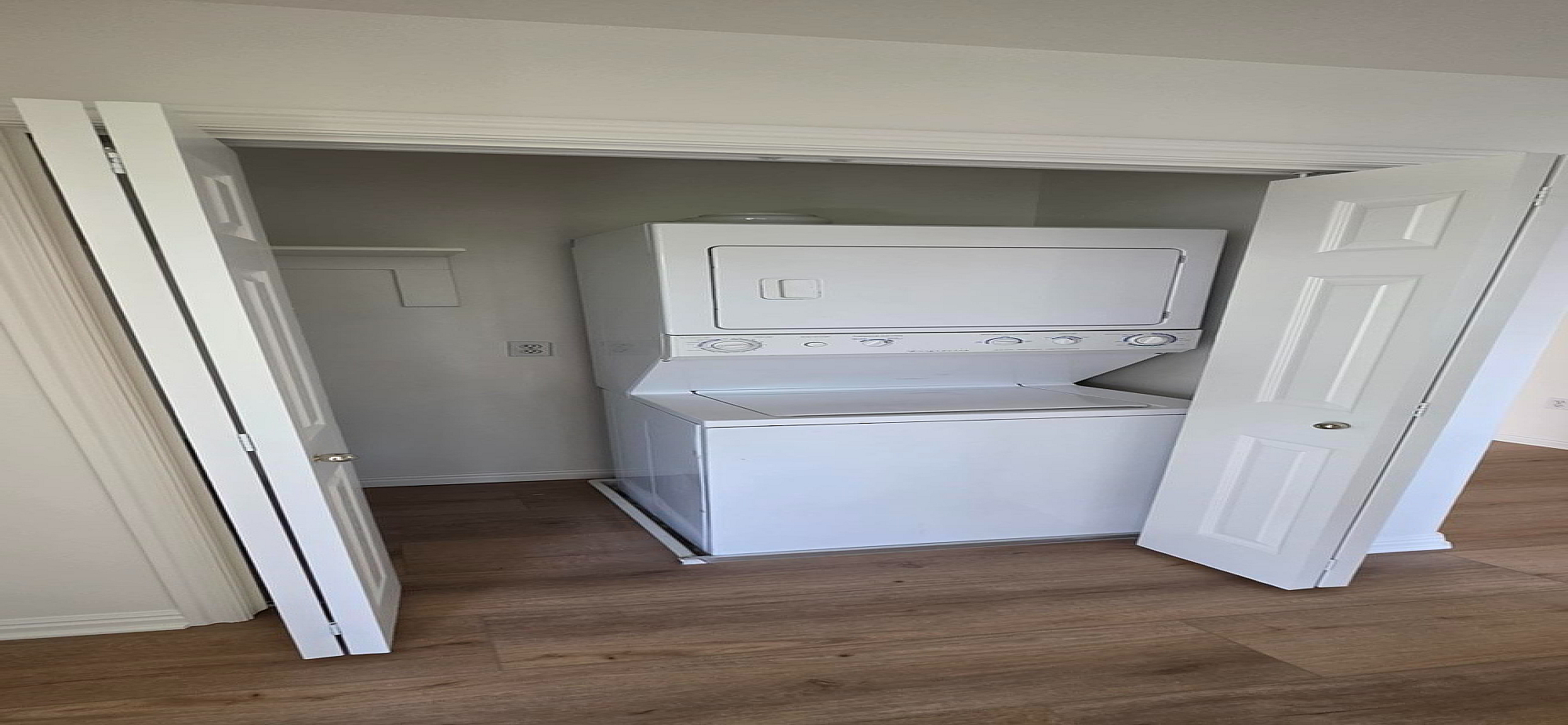 Convenient in-unit laundry with modern stacked washer and dryer, tucked away behind stylish folding doors.