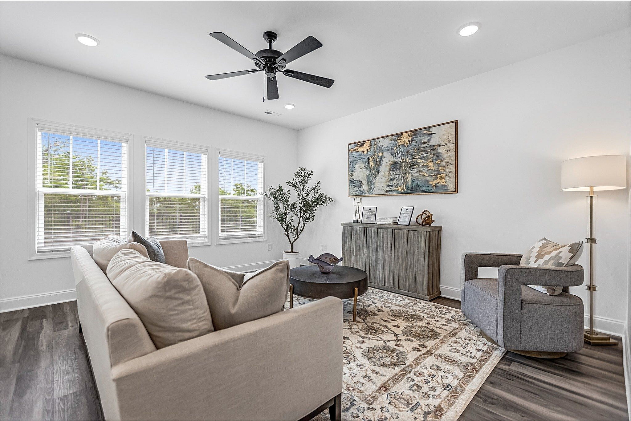 Bright and elegant living room with modern decor, featuring a cozy beige sofa, stylish armchair, and natural light streaming through large windows.