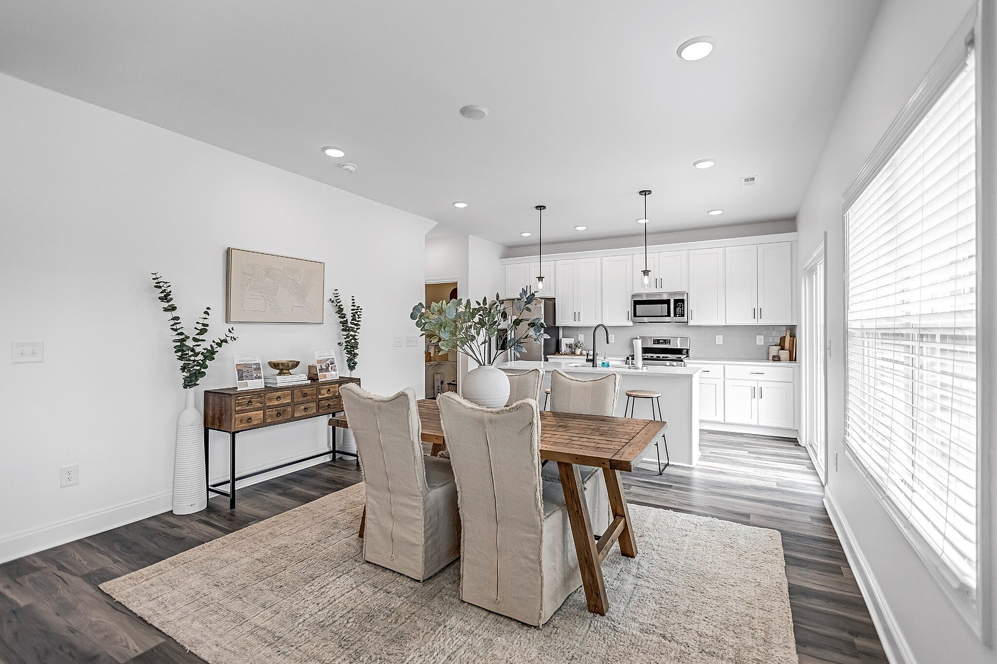 Bright and airy open-concept kitchen and dining area featuring modern white cabinets, sleek countertops, and elegant dining furniture with abundant natural light.