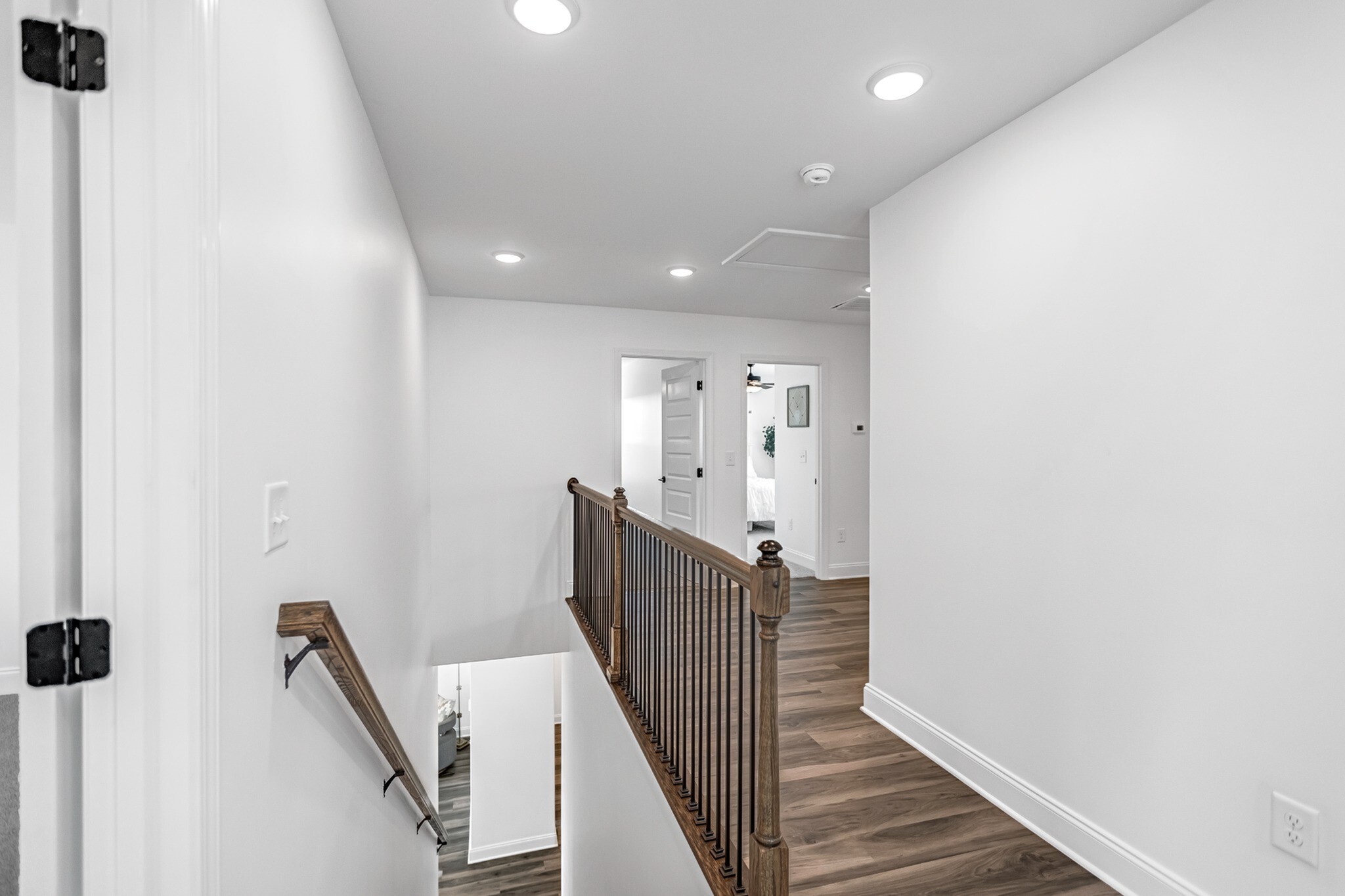 Bright and modern hallway with elegant wooden railing, leading to cozy bedrooms in a stylish apartment.