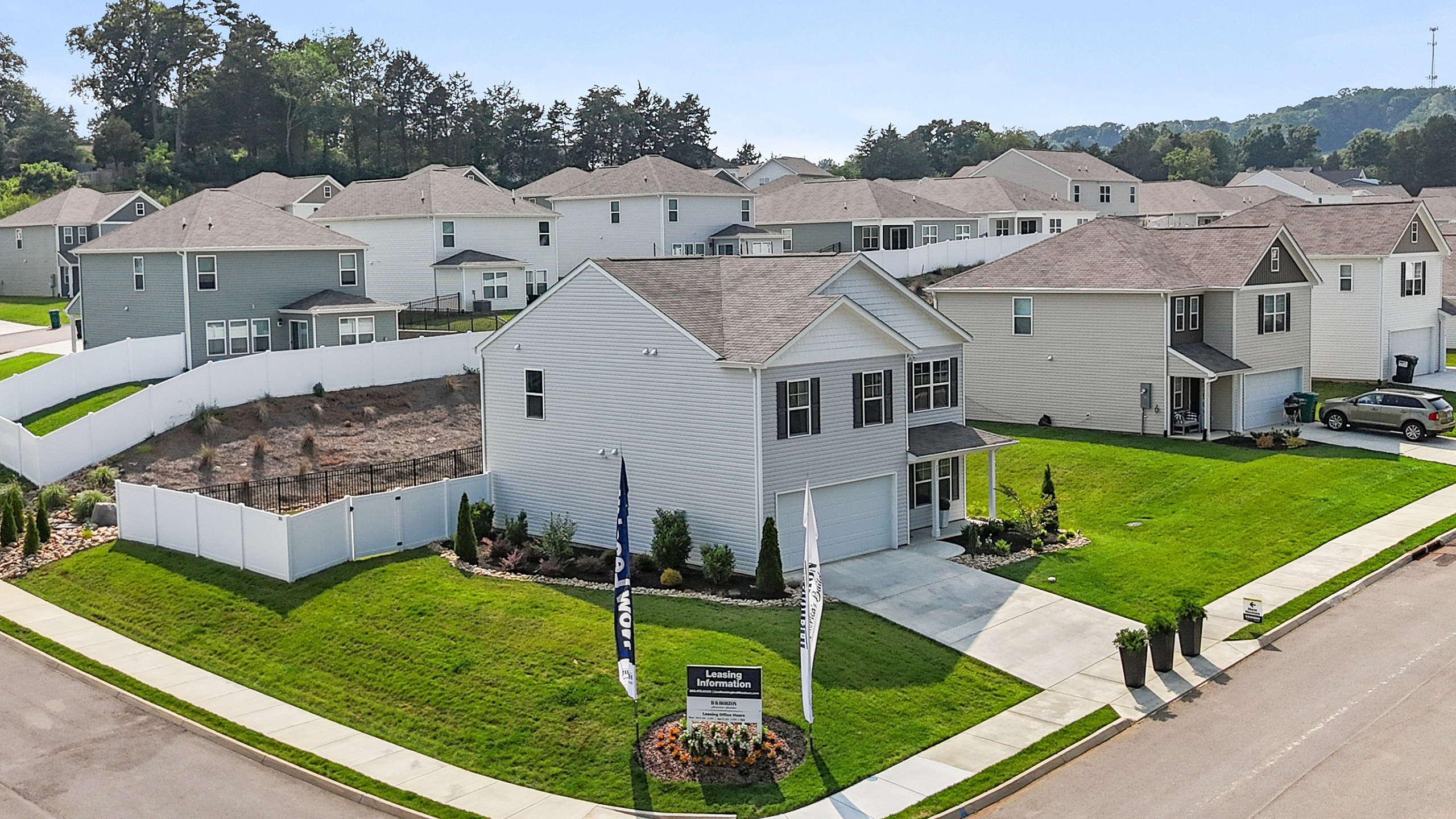 Charming suburban neighborhood corner with modern, spacious homes and well-maintained green lawns under blue skies, ideal for family living.
