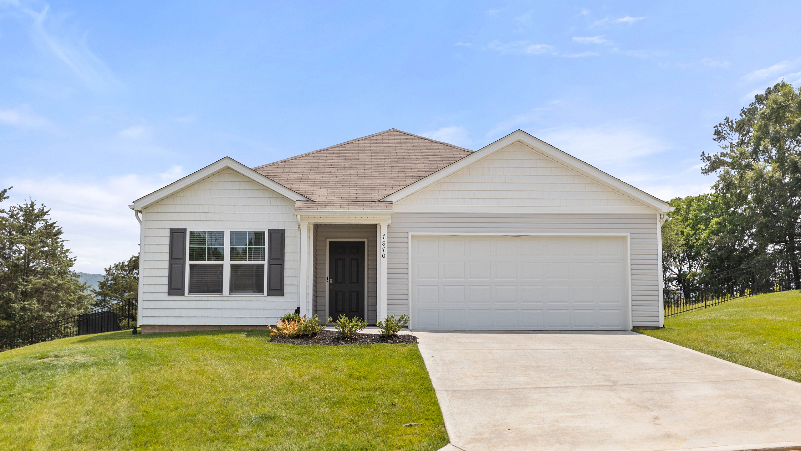Charming single-story home with a spacious front lawn, modern exterior, and attached garage under a clear blue sky.