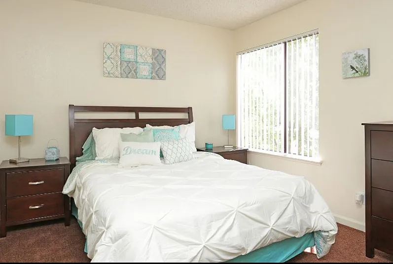 Bright and cozy bedroom with modern furnishings, featuring a plush bed, elegant nightstands, and large window for natural light.