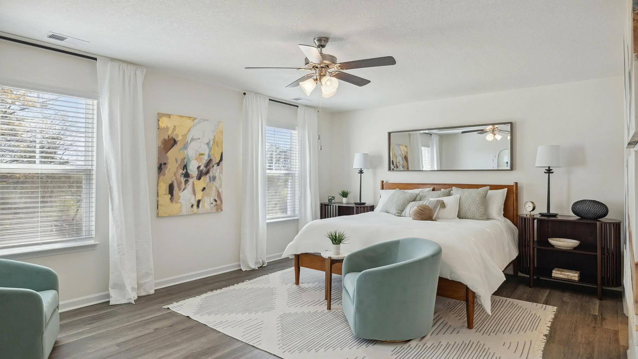 Elegant bedroom with modern decor, featuring a cozy bed, stylish chairs, and large windows providing ample natural light.
