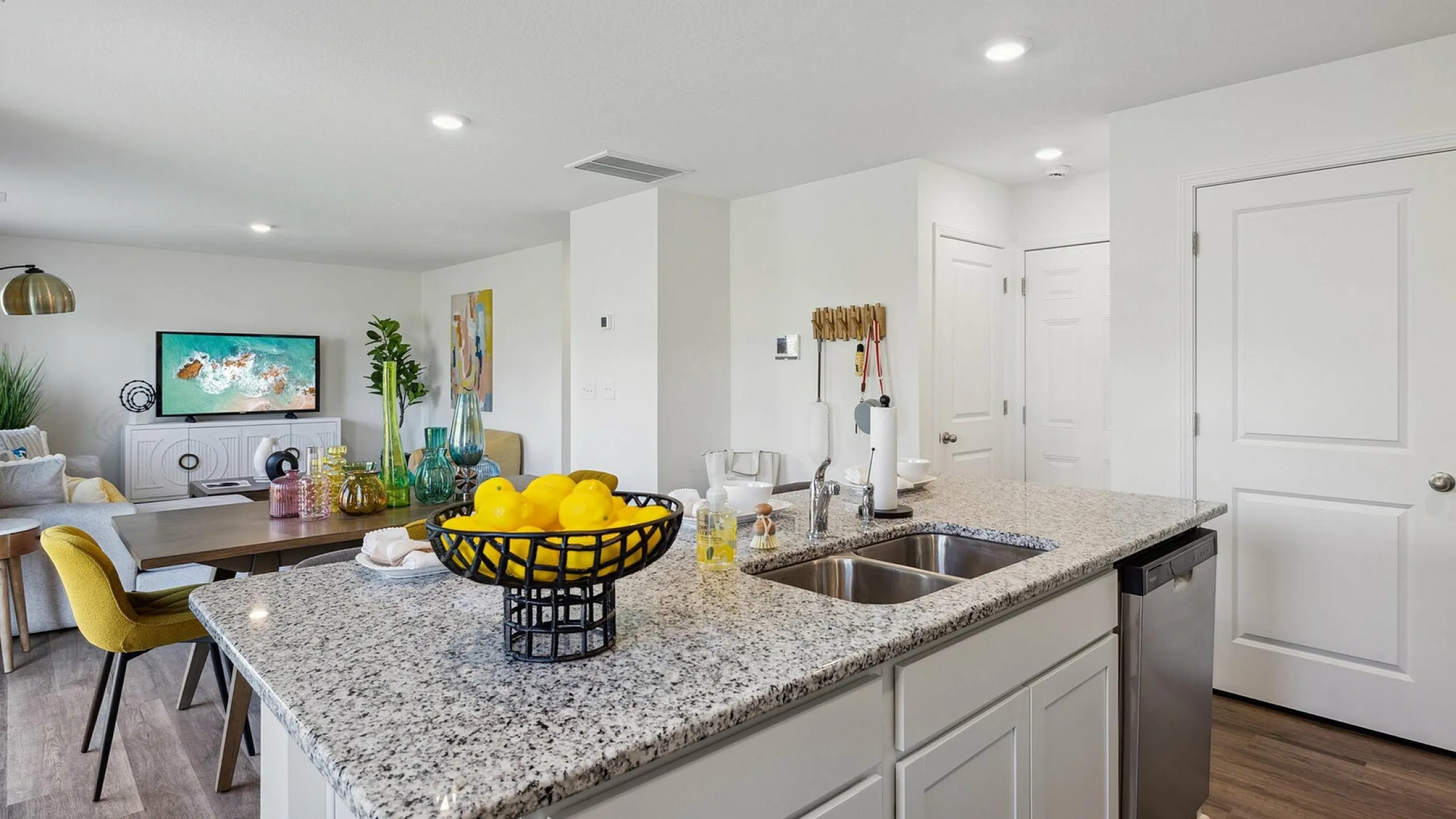 Modern open-plan kitchen and living area with sleek granite countertops and vibrant decor, creating a welcoming atmosphere.