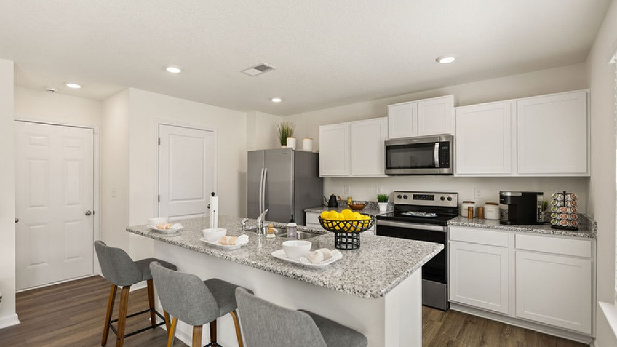 Modern kitchen with sleek white cabinets, granite countertops, and a stylish breakfast bar with seating for four.