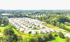 Aerial view of a picturesque suburban neighborhood with rows of charming houses surrounded by lush greenery and scenic landscapes.