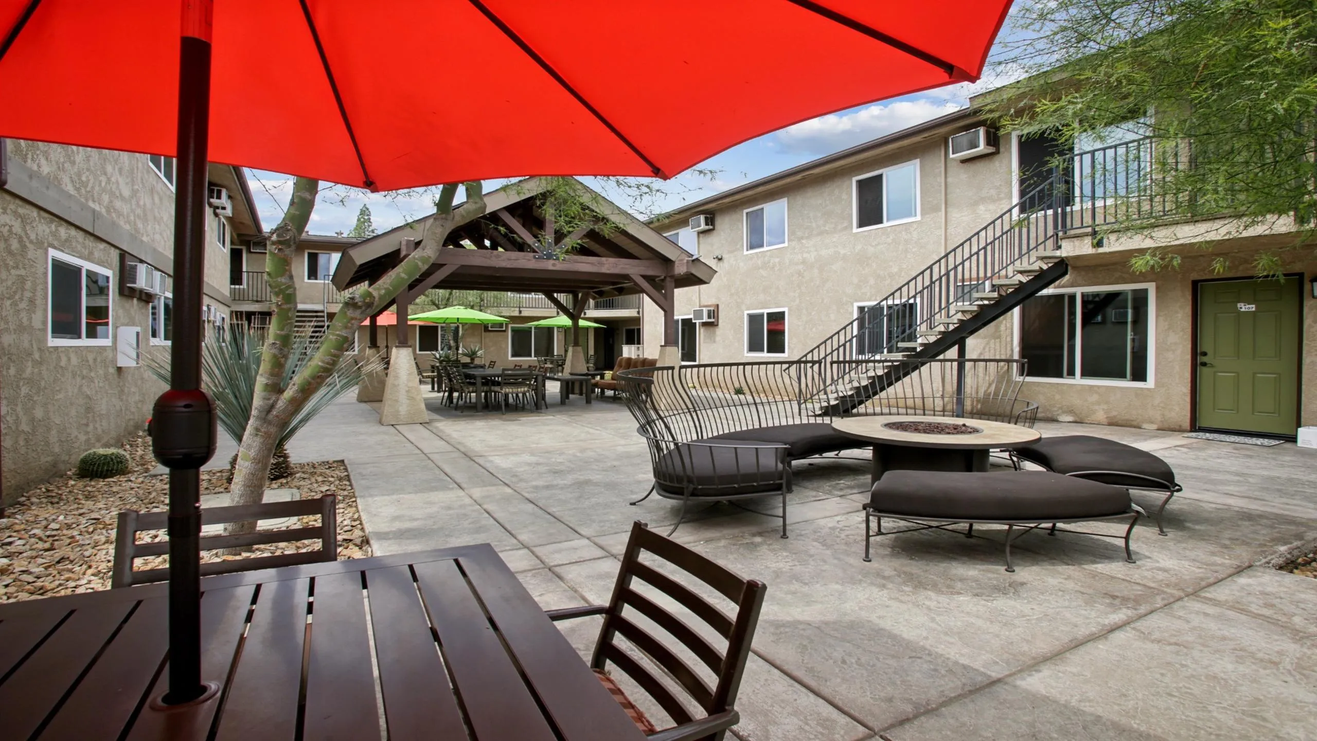 Inviting courtyard with cozy seating, vibrant umbrellas, and a modern fire pit for ideal outdoor relaxation and socializing.