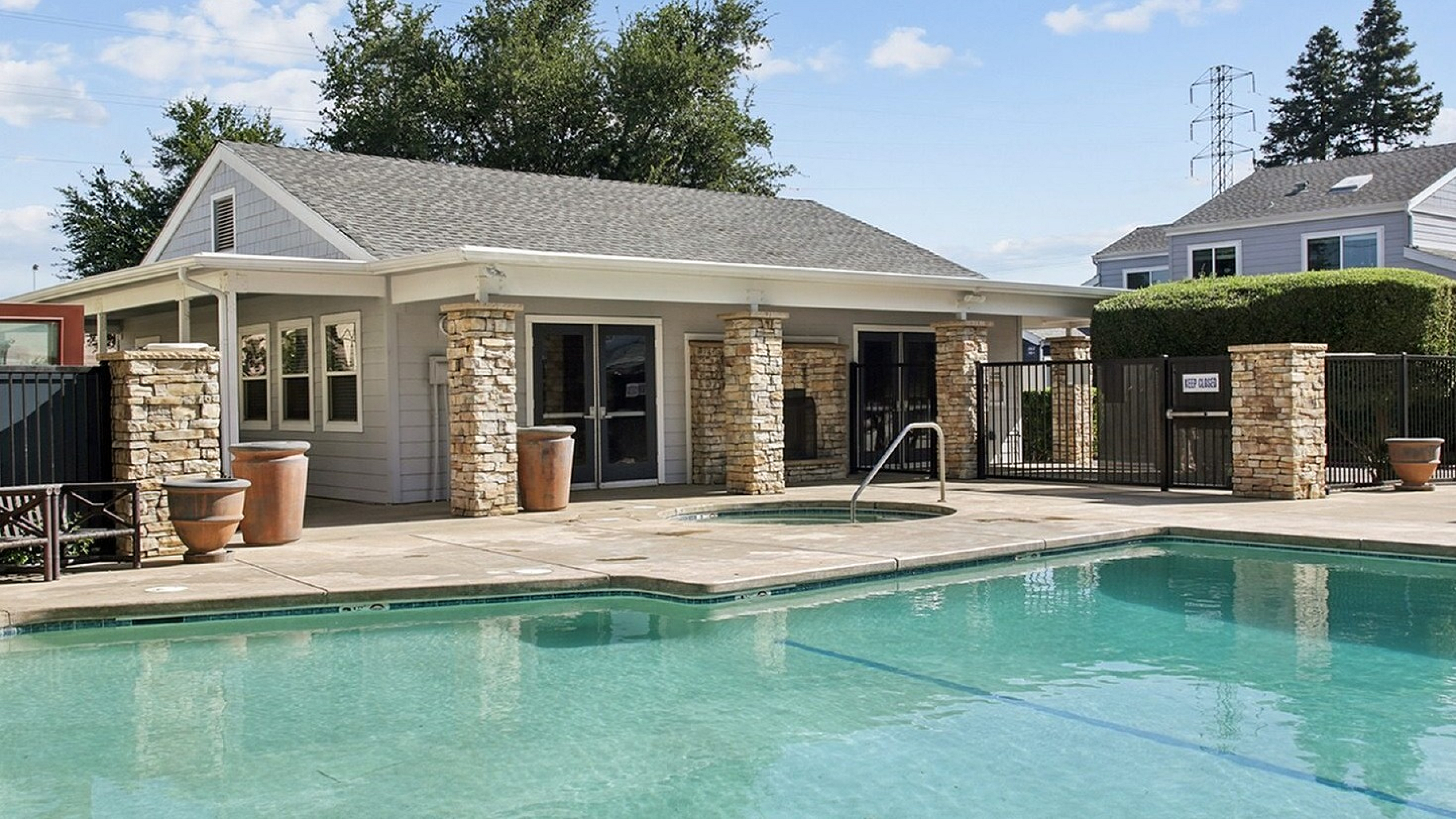 Inviting community pool surrounded by modern stone architecture and lush greenery, offering a serene escape for residents.
