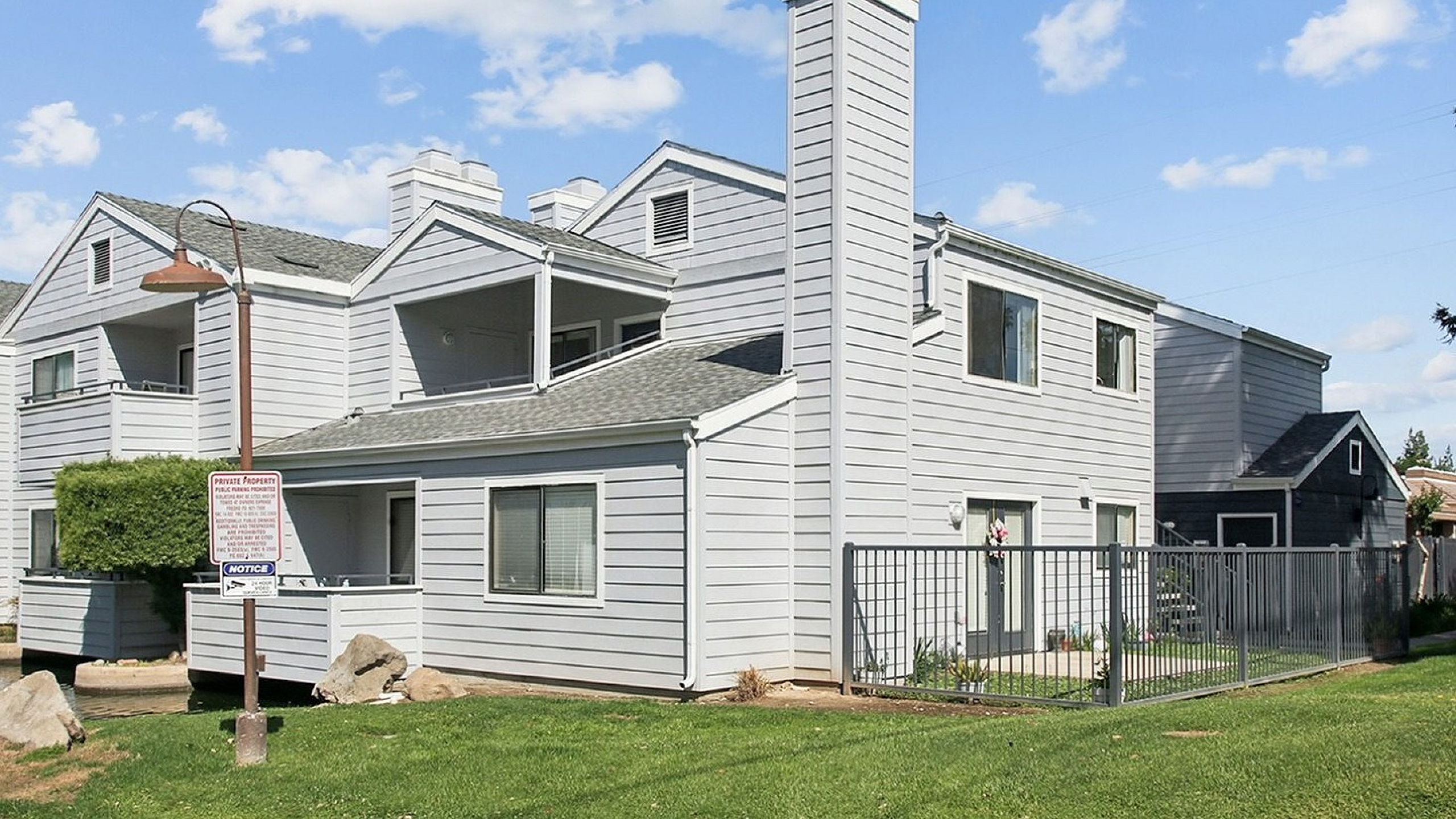 Modern two-story apartment building with charming balconies and a landscaped front lawn, perfect for comfortable living.