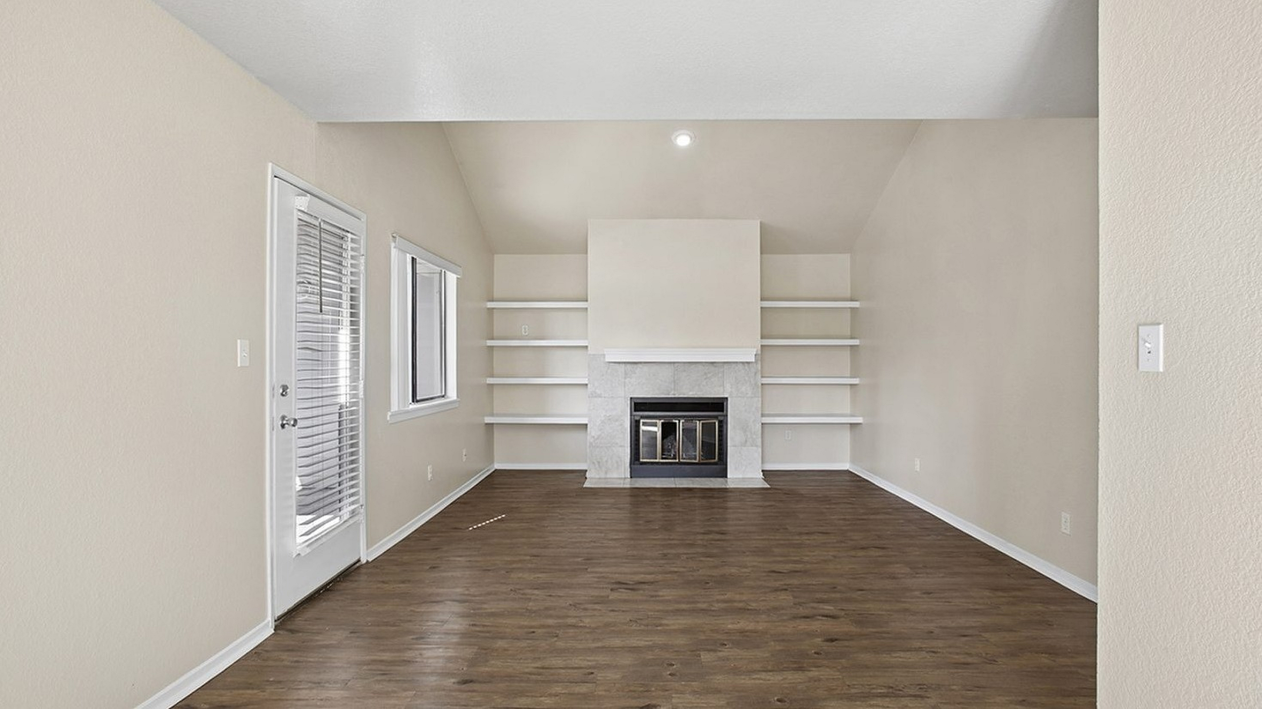 Elegant living room featuring a modern fireplace, built-in shelves, and rich wood flooring with ample natural light.