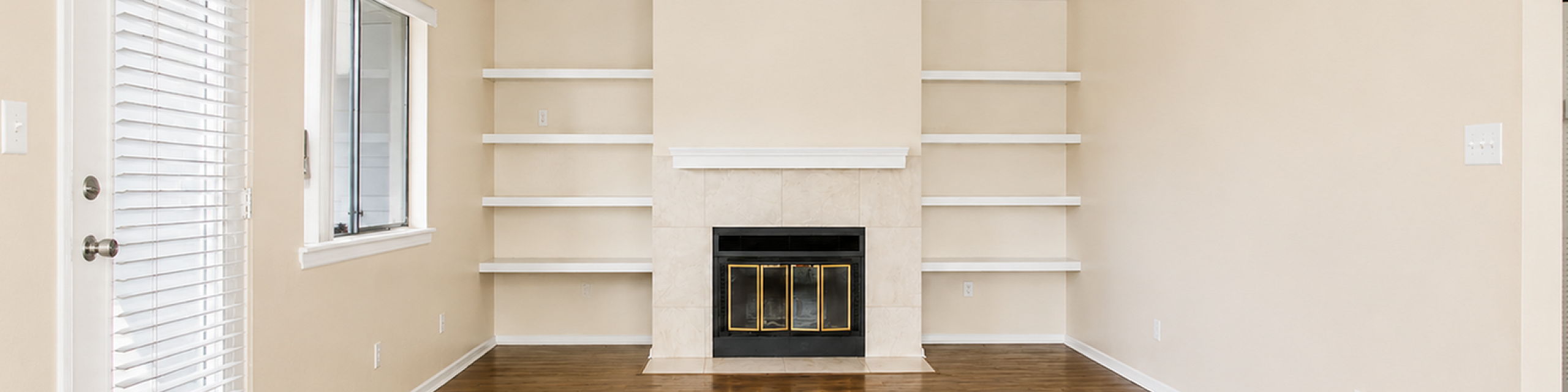 Elegant living room with warm hardwood floors, built-in shelves, and a classic fireplace, perfect for cozy evenings.