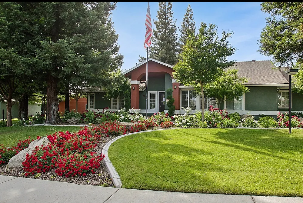 Charming residential home with lush landscaping, vibrant flower beds, and mature trees in a serene neighborhood setting.