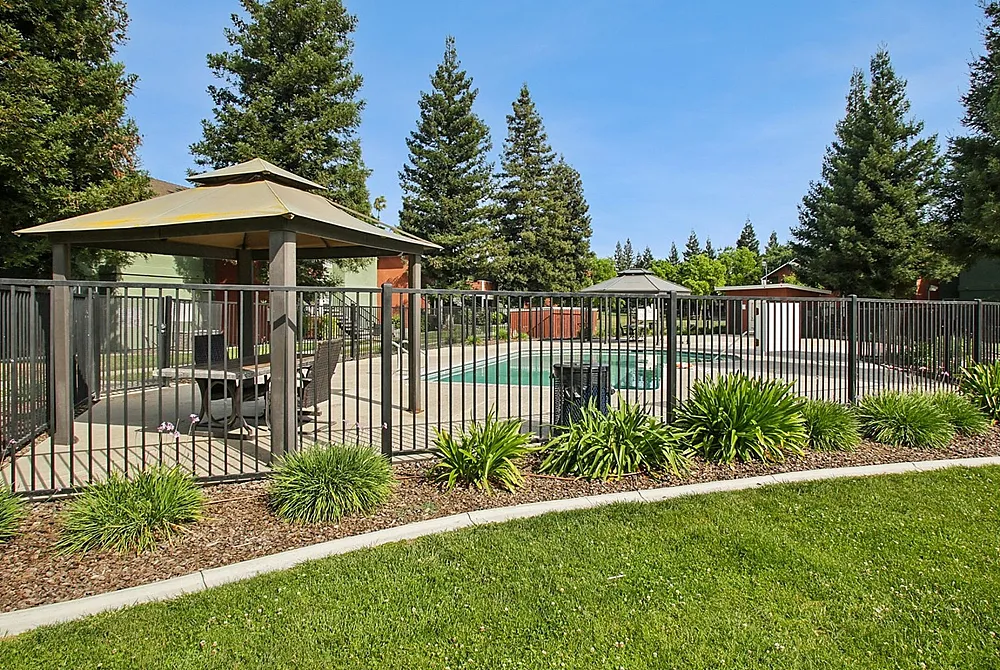 Serene outdoor pool area with lush greenery and elegant gazebo, perfect for relaxation and leisure.