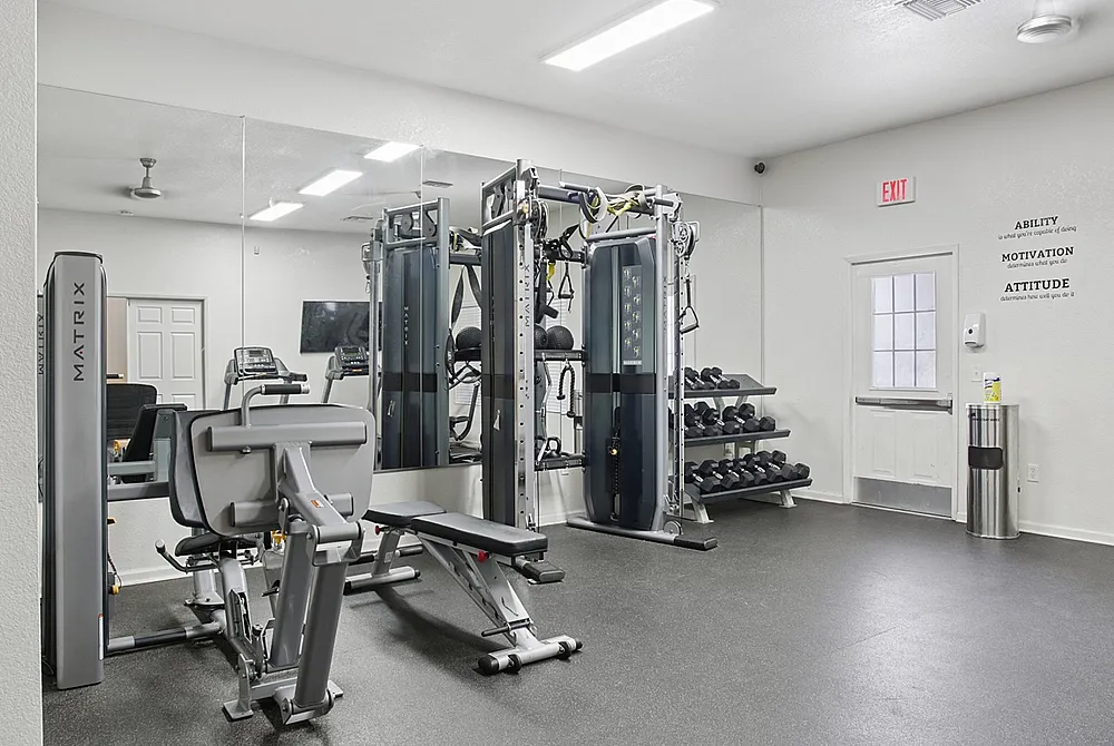 Modern fitness center equipped with state-of-the-art exercise machines and free weights, mirrored walls, and motivational quotes.
