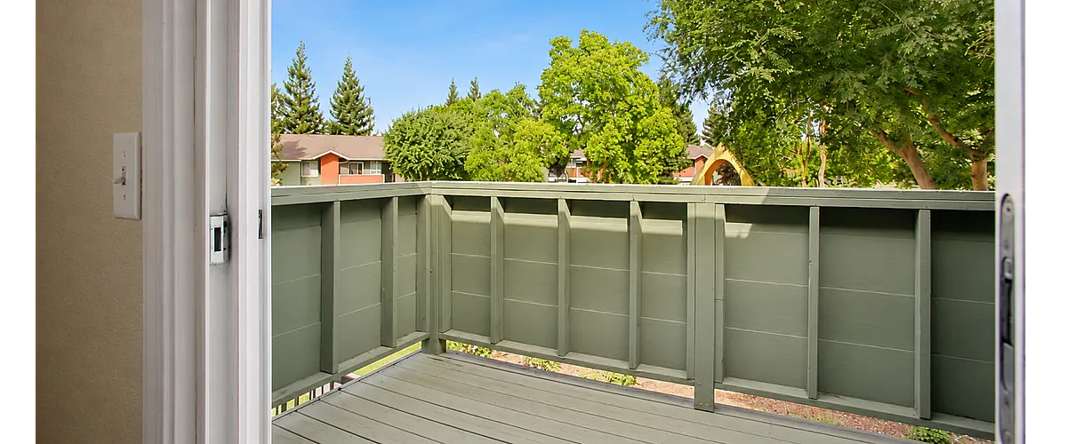 Charming balcony view showcasing lush greenery and residential backdrop, perfect for relaxation and outdoor enjoyment.