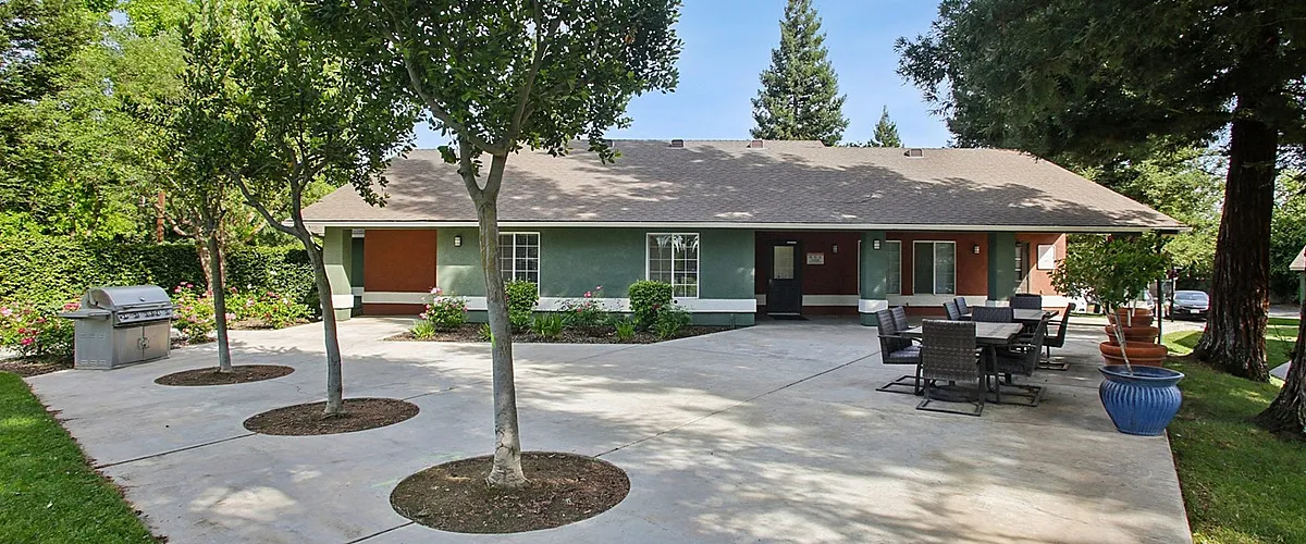 Charming outdoor patio area with lush greenery, ample seating, and a modern grill, perfect for relaxing and entertaining.