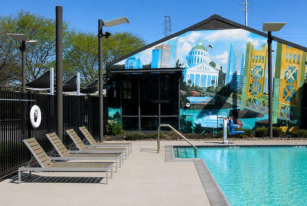 Vibrant poolside area with modern lounge chairs and a colorful mural backdrop, perfect for relaxation and leisure.