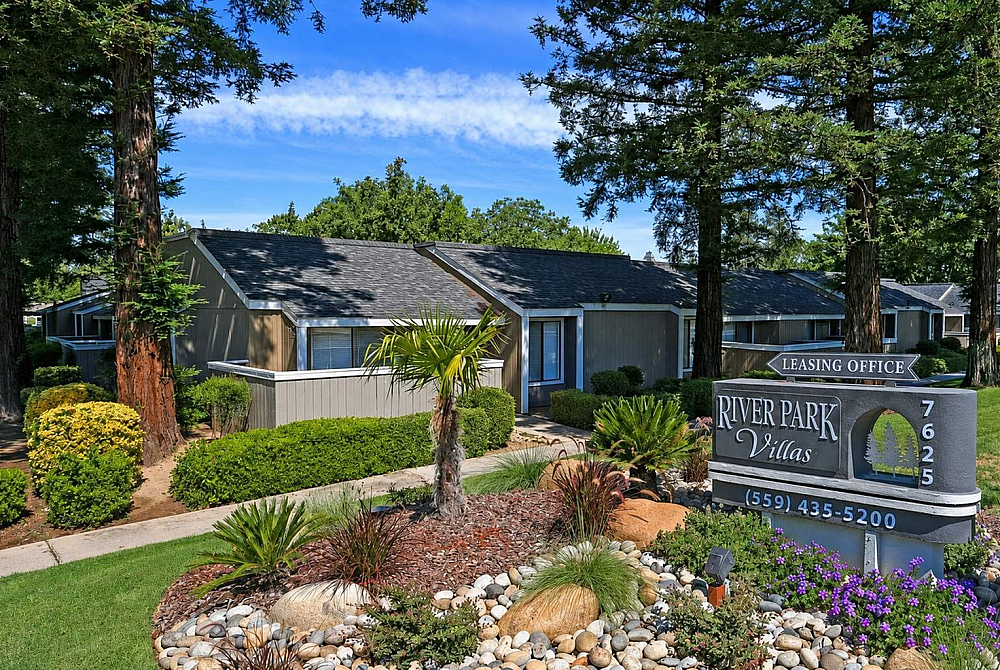 Charming River Park Villas surrounded by lush greenery and vibrant landscaping, offering serene living in a beautiful setting.