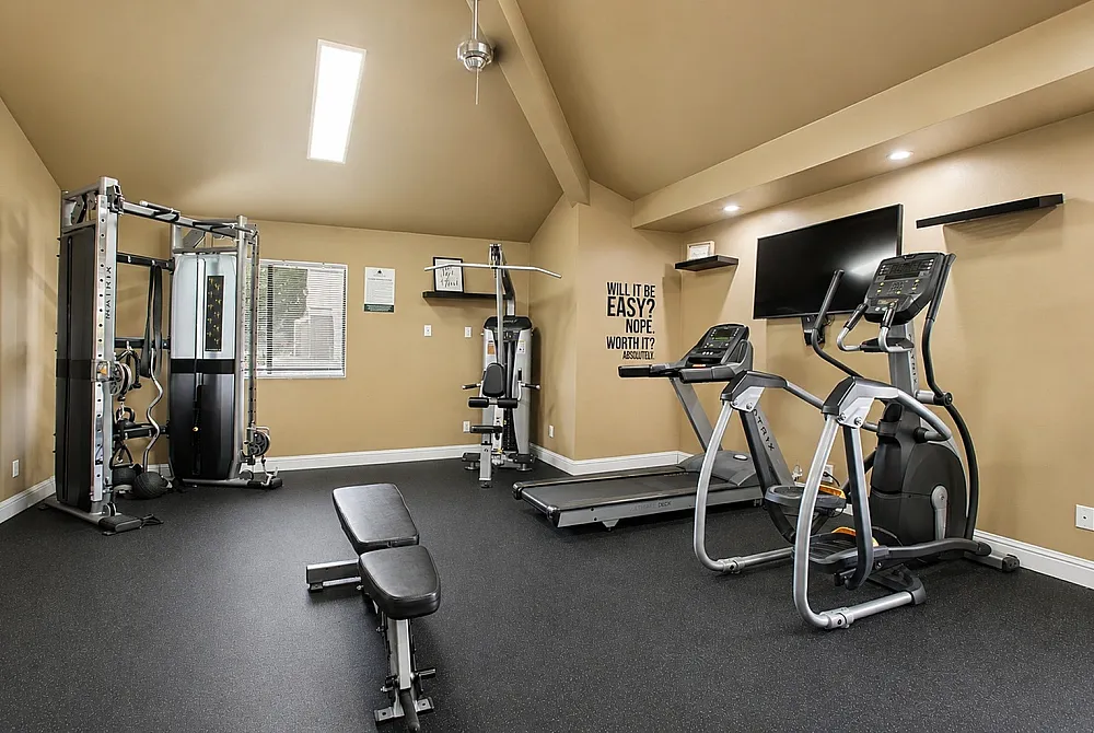 Modern apartment gym equipped with state-of-the-art fitness machines, sleek treadmill, and motivational wall art for an inspiring workout.
