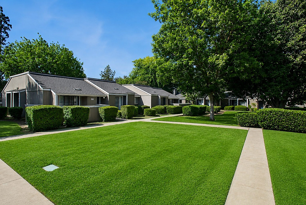 Charming cottage-style apartments nestled in lush greenery, offering serene pathways and vibrant landscapes.