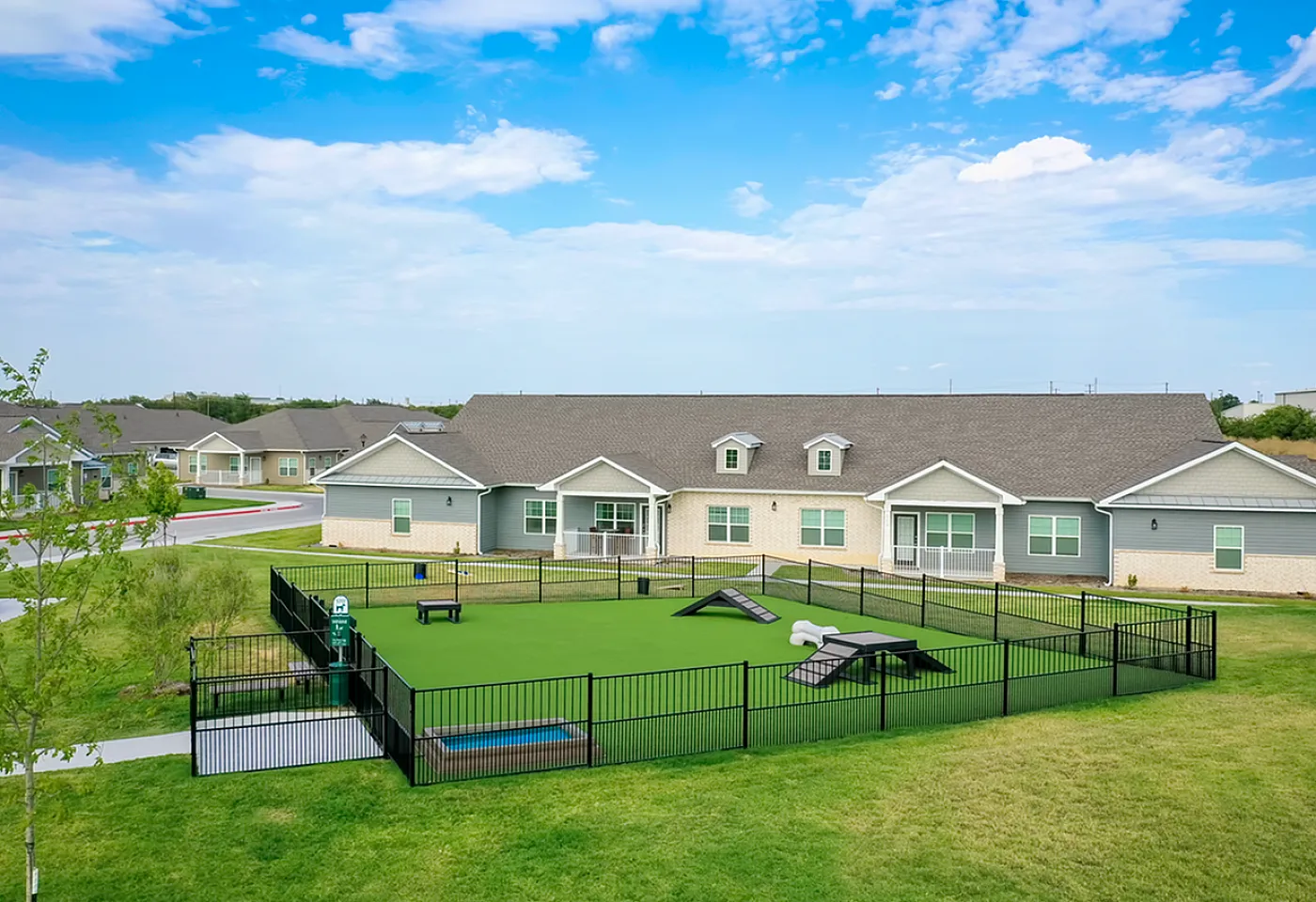 Charming residential community with modern houses and a fenced green space, perfect for enjoying sunny days in a peaceful neighborhood setting.