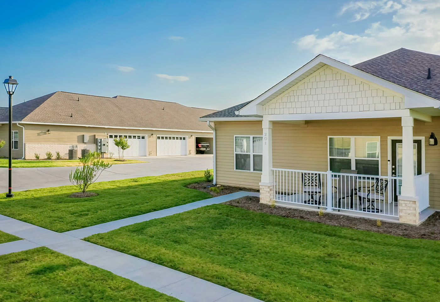 Charming residential unit with a spacious porch and manicured lawn in a serene neighborhood setting.