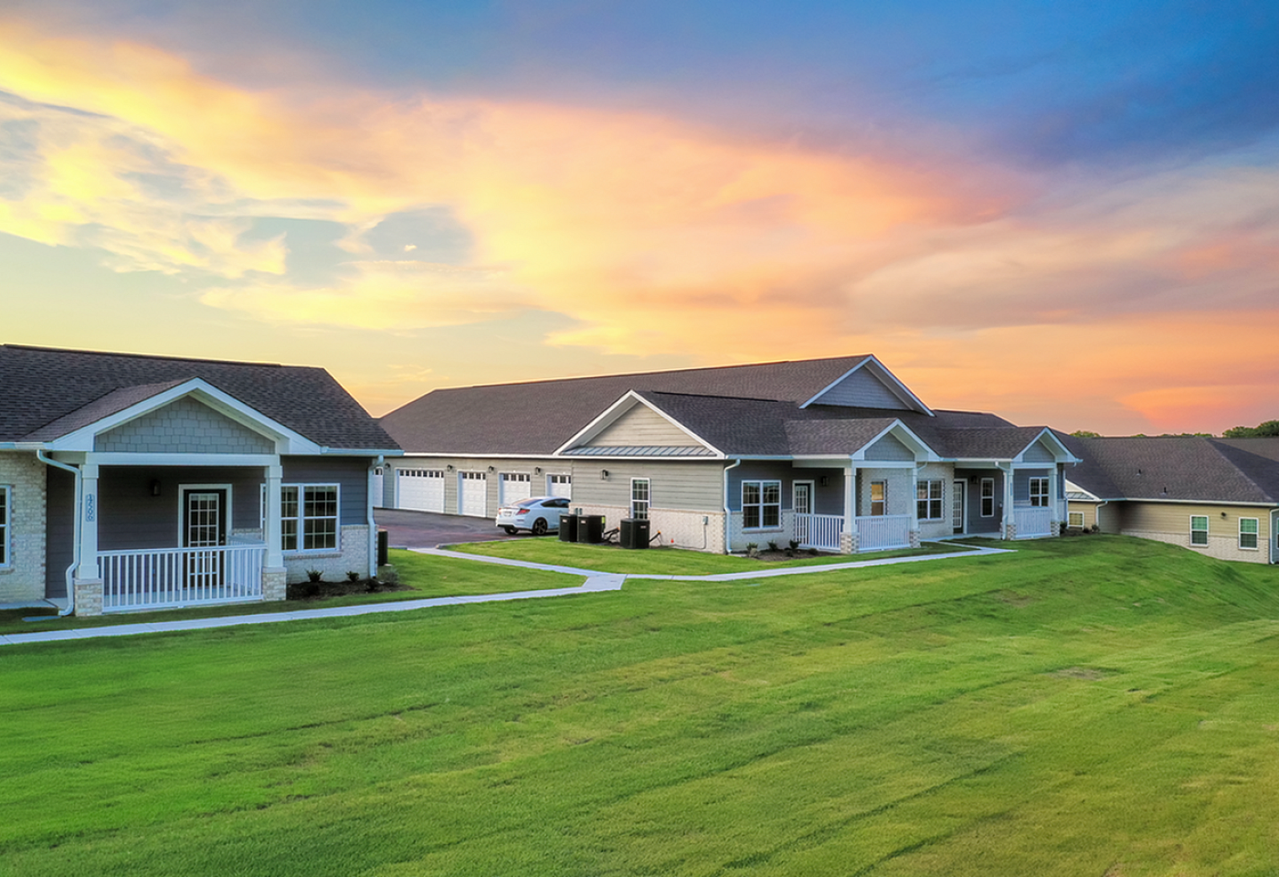 Charming suburban homes with neat lawns basked in a vibrant sunset sky, offering serene and picturesque living.