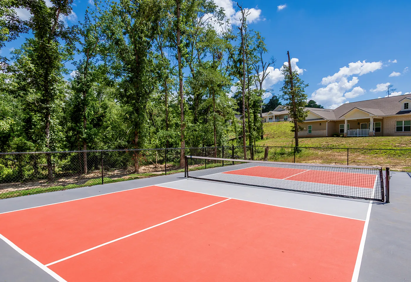 Vibrant outdoor pickleball court surrounded by lush greenery, perfect for active living in a serene community setting.