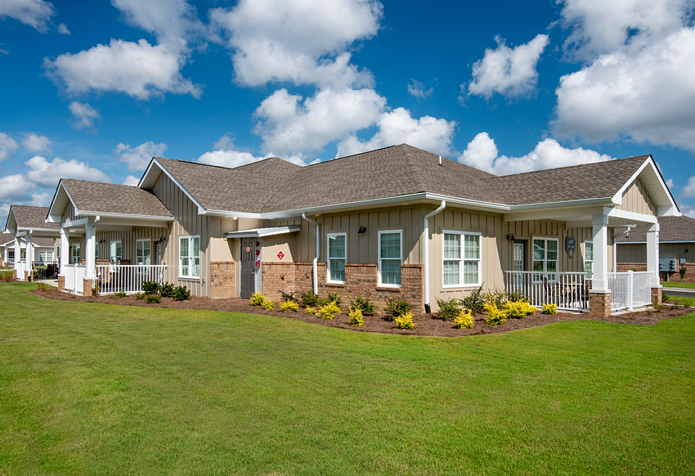 Charming single-story home featuring a welcoming porch, manicured lawn, and modern exterior design under a bright blue sky.