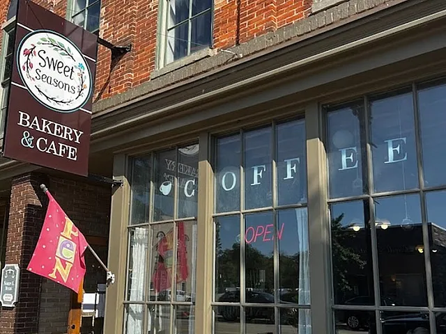Exterior of Sweet Seasons Bakery & Cafe with vibrant flowers and an inviting open sign.