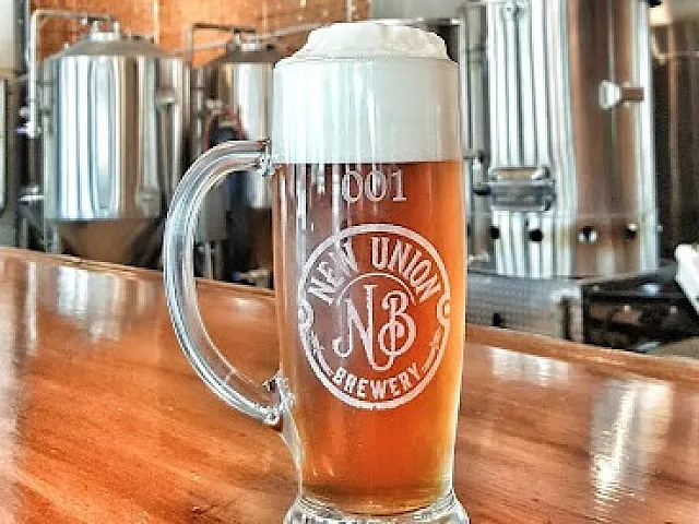 Inviting craft beer in a glass mug with frothy top at a modern brewery setting.