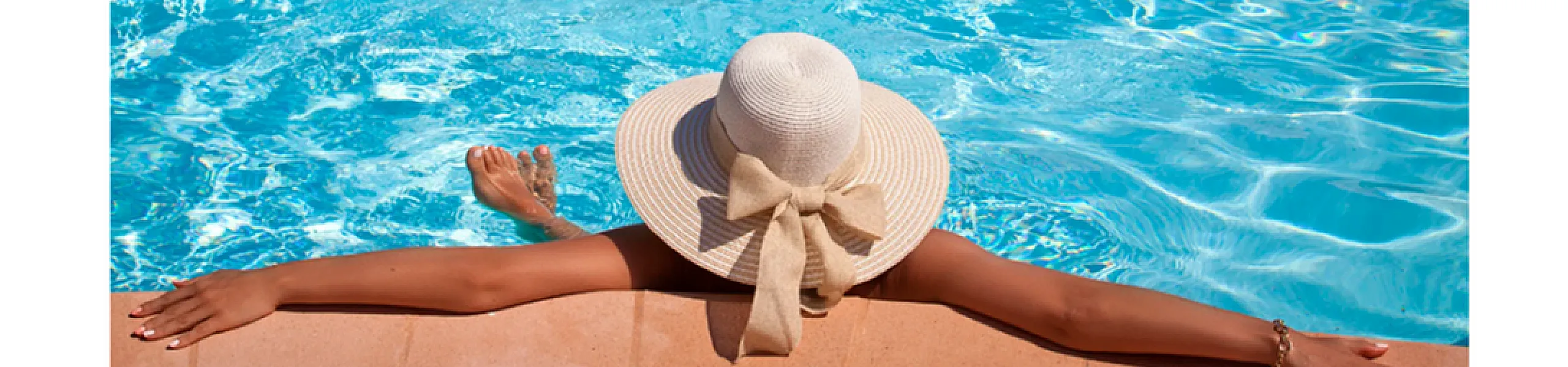 Relaxing poolside with a sun hat and vibrant blue water under a clear sky.