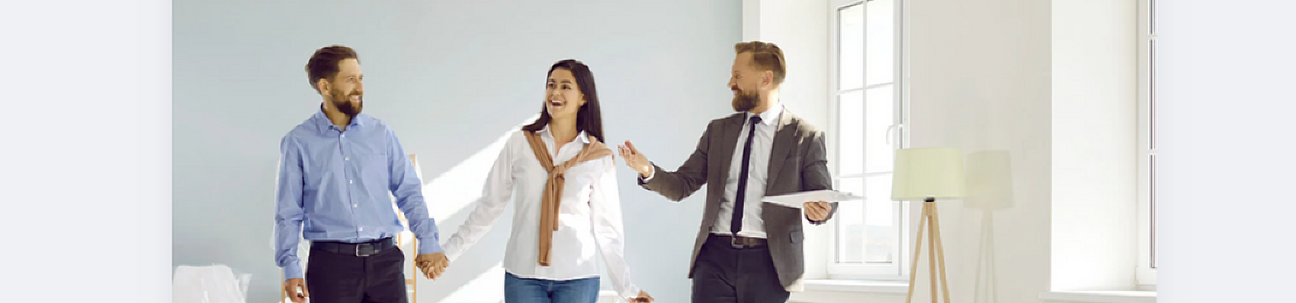 Couple touring a modern, bright apartment with a real estate agent.