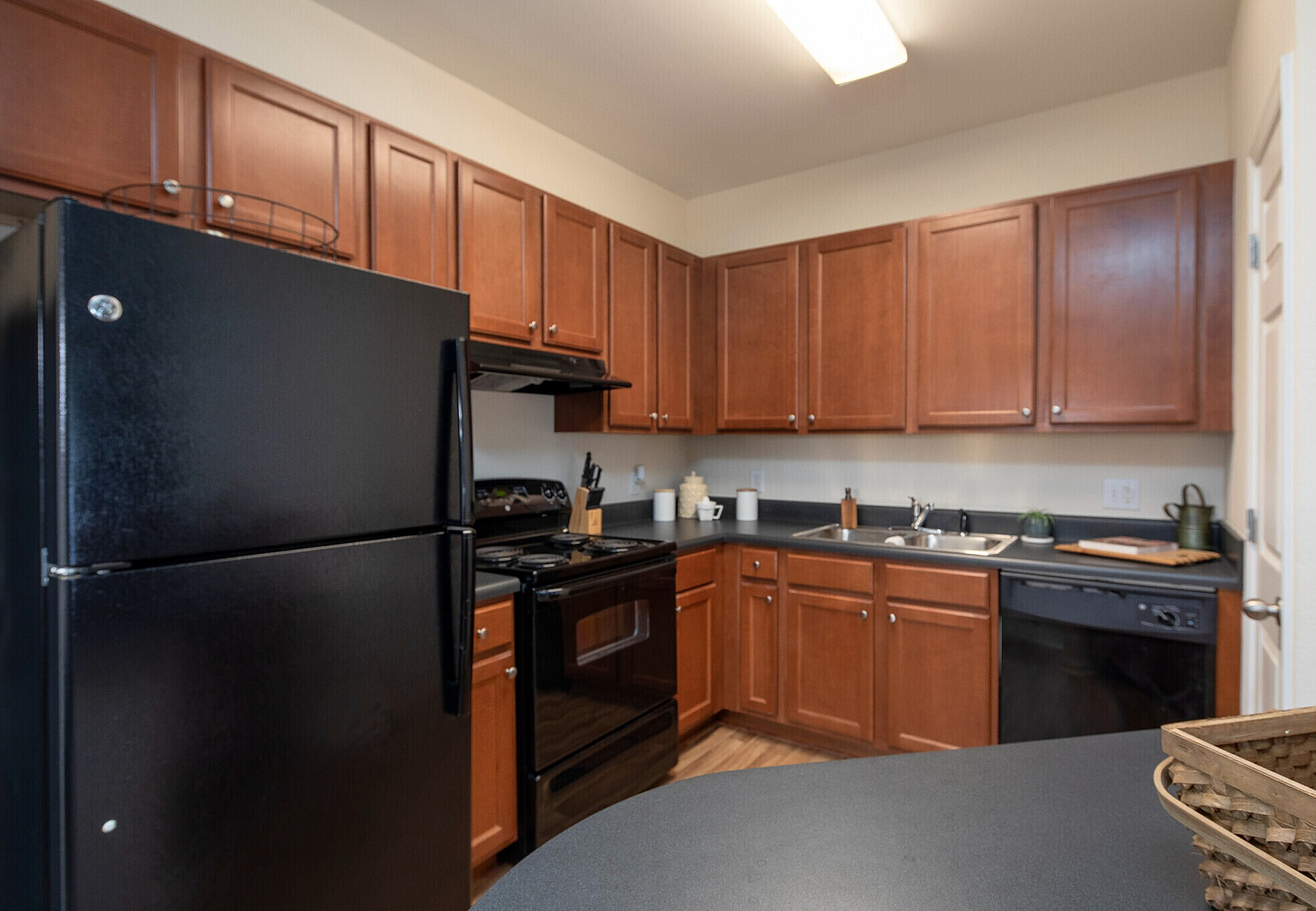 Modern kitchen with rich wooden cabinetry, sleek black appliances, and ample counter space, perfect for gourmet cooking.
