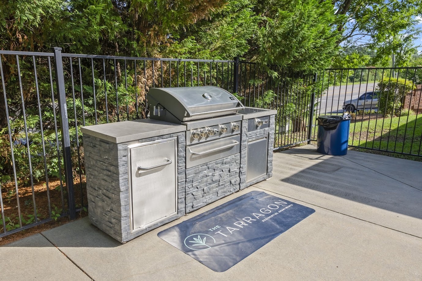 Modern outdoor grill area with stainless steel barbecue and scenic greenery.