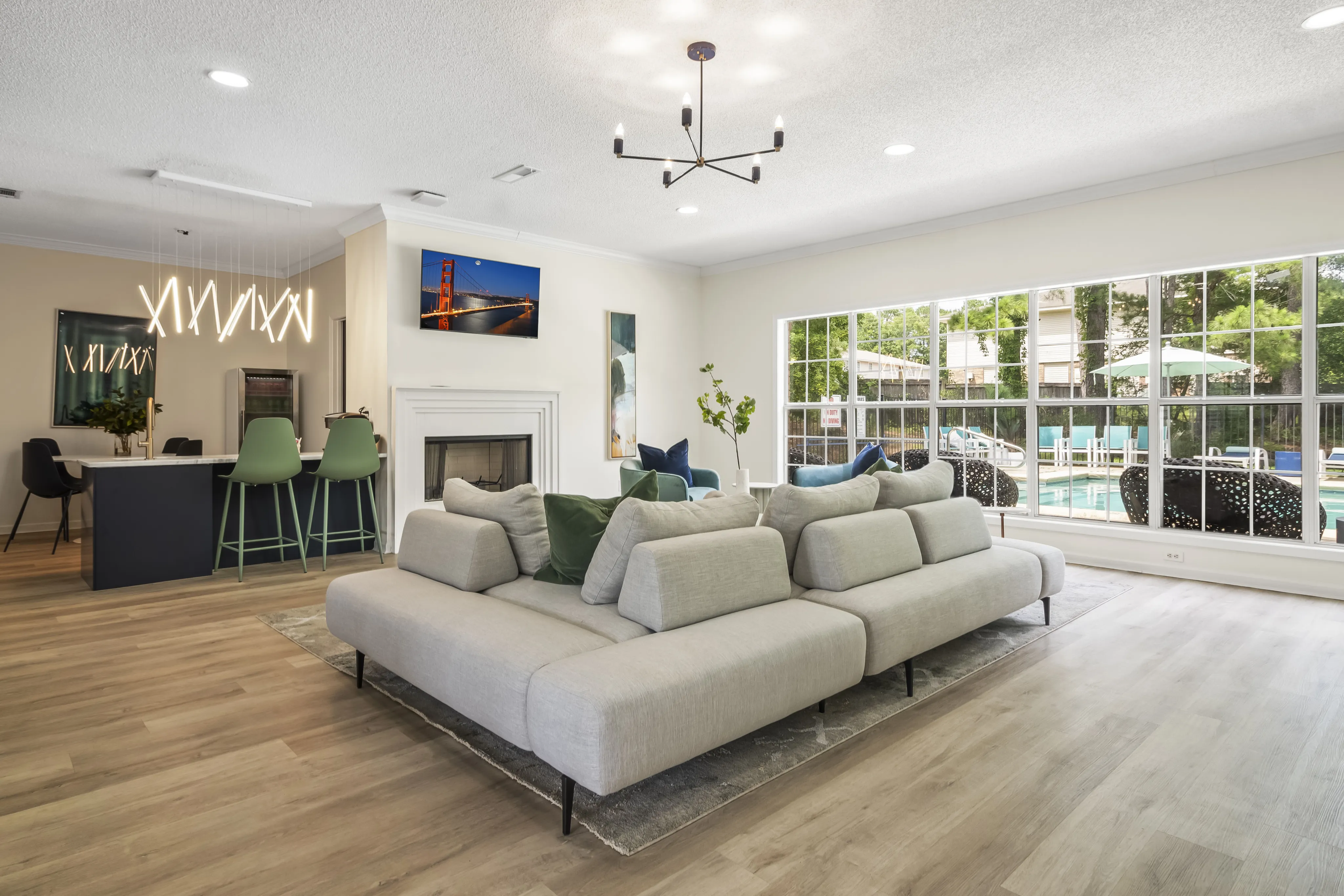 Stylish open-concept living room with modern furniture, large windows, and a view of the pool.