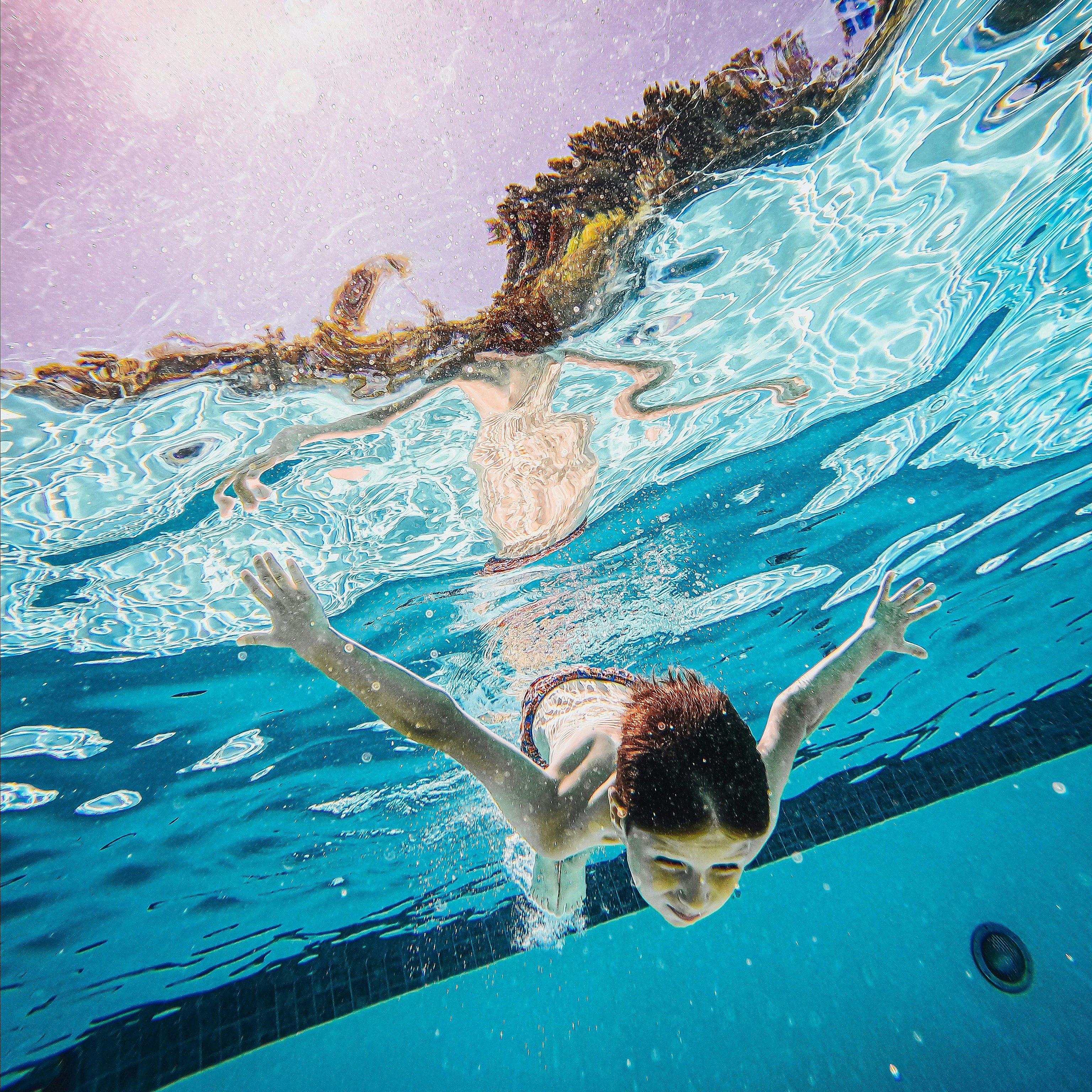 Vibrant underwater view of a child swimming in a sunlit pool, capturing a joyful summer moment.