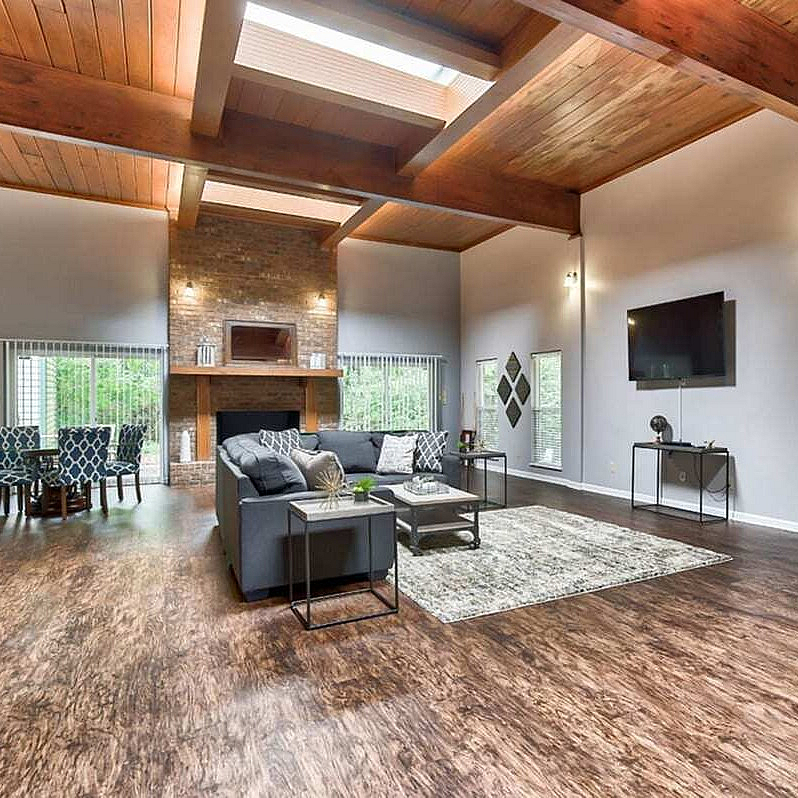 Expansive living room with vaulted wooden ceilings, elegant fireplace, and chic modern decor.