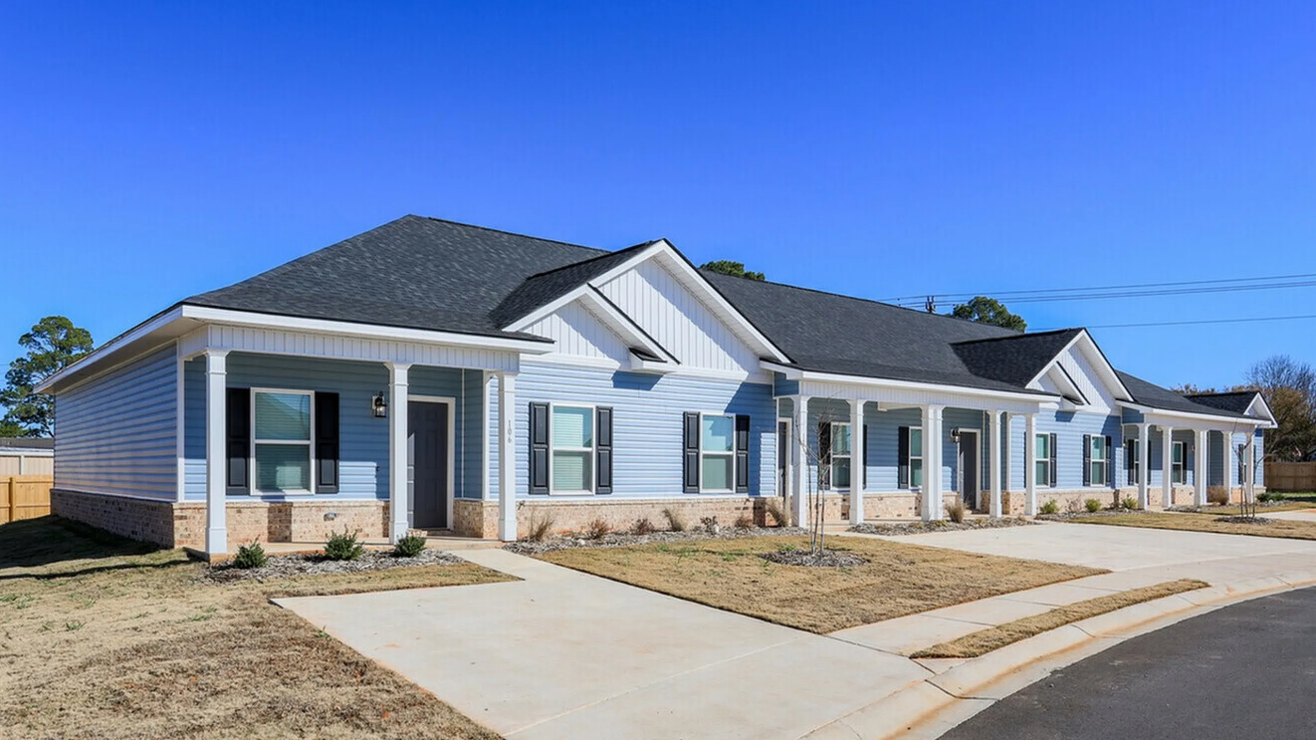 Inviting row of Townhome with blue siding and white trim under a clear sky.