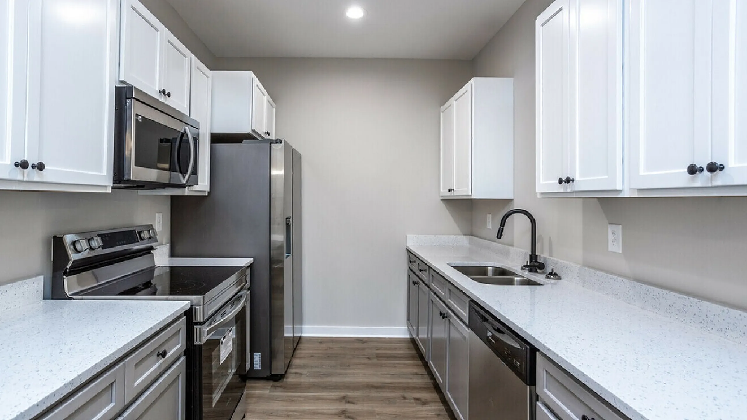 Modern kitchen featuring sleek white cabinetry, stainless steel appliances, and elegant countertops.