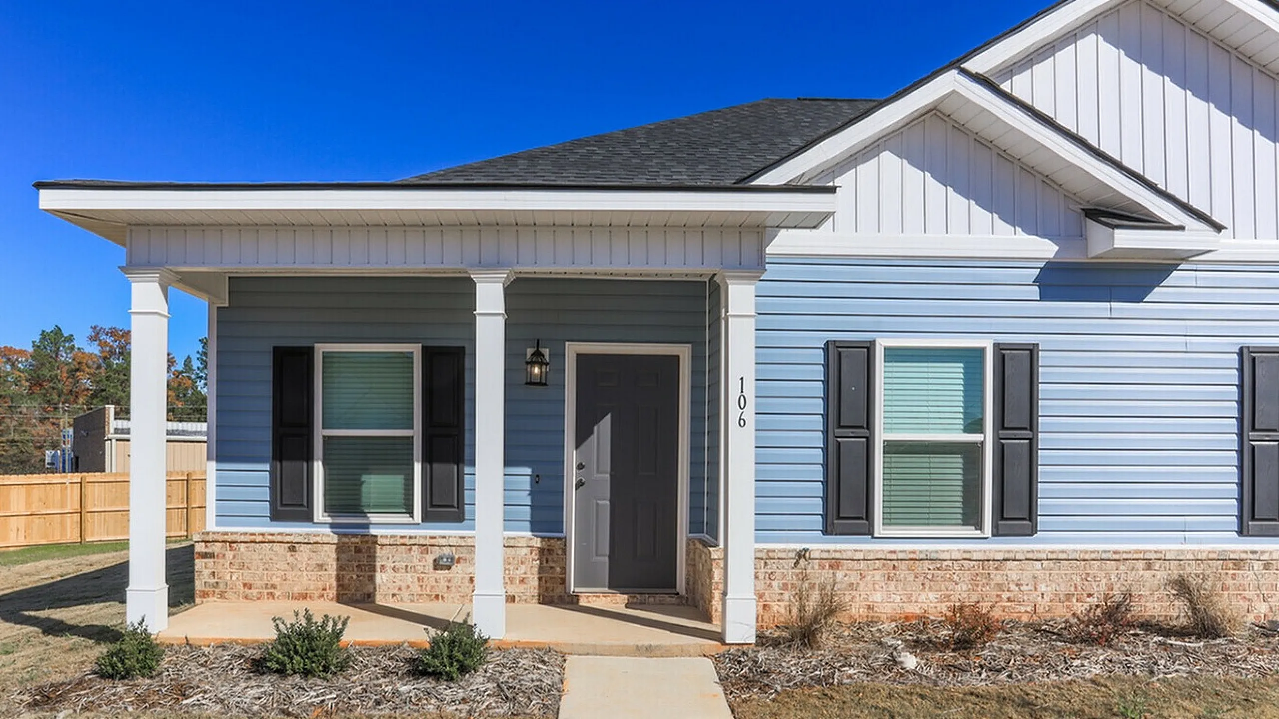 Charming blue townhome exterior with a welcoming front porch and elegant black shutters.