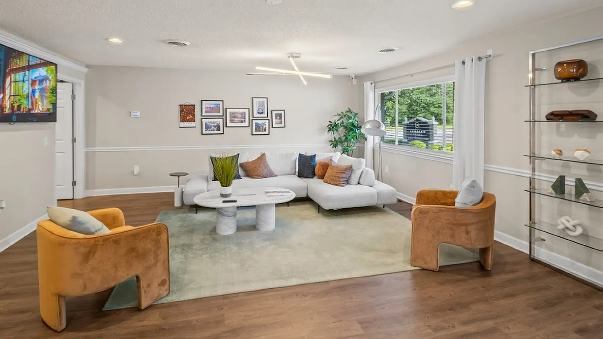 Inviting living room with white sectional sofa, modern decor, large window, and warm wooden floor.
